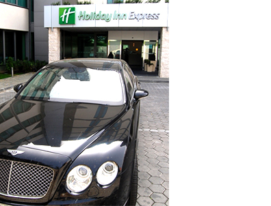 Bentley sedan parked in front of the Holiday Inn Express hotel in Portugal.